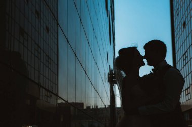 Arka plandaki ayna binalardaki siluet düğün çifti