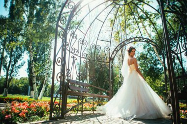 Genç, güzel bir gelin parktaki bir çardakta duruyor..