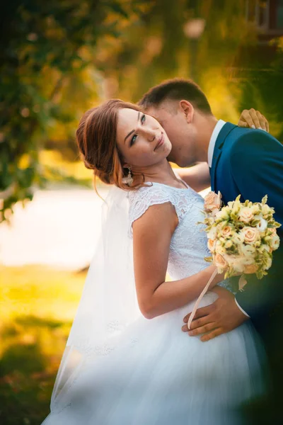 Pár ženich a nevěsta objímání a líbání na pozadí přírodního parku — Stock fotografie