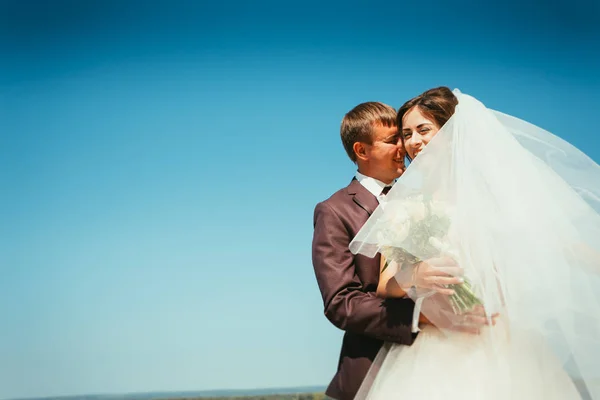 Jonge bruid en bruidegom paar op de hemelachtergrond — Stockfoto