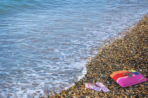 Beach Ayakkabı ve sahilde havlu. — Stok fotoğraf