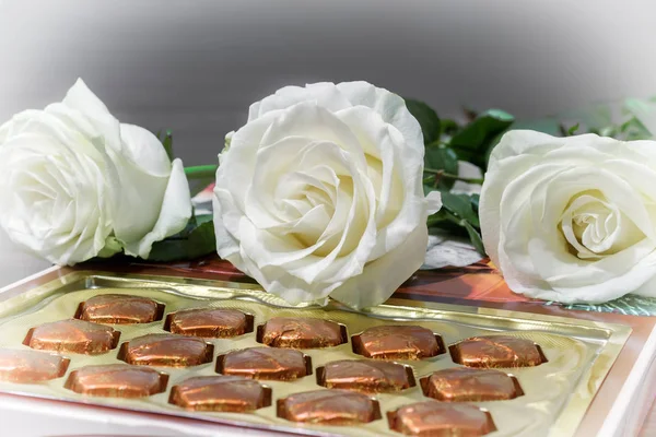 Białych róż i czekoladek w prezencie. — Zdjęcie stockowe