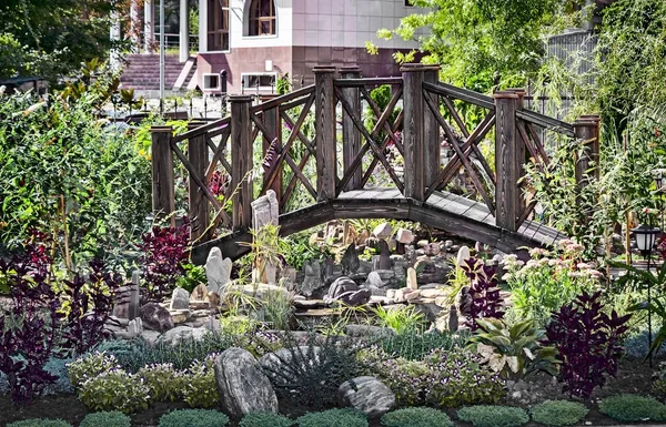 景观设计 用石头和植物装饰的人工池塘上的小木桥 — 图库照片