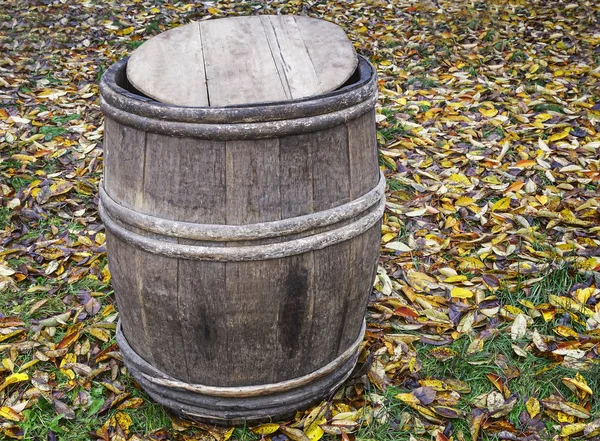 Eichenfass auf dem Boden vor einem Hintergrund aus Herbstblättern. — Stockfoto