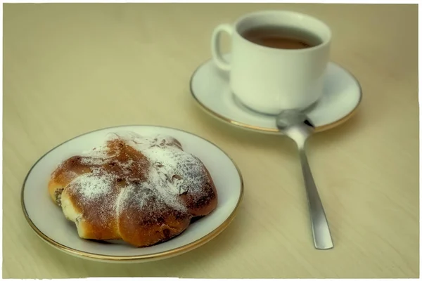 Uma xícara de café e rolo de canela em uma mesa de madeira . — Fotografia de Stock