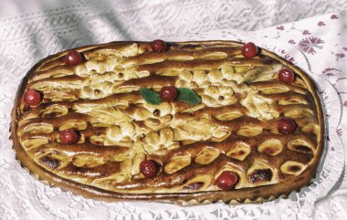 Güzel kiraz büyük bir lezzetli pasta ile dekore edilmiş bir dantel peçete üzerinde masada.