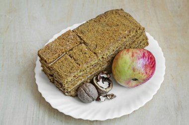 Bir pasta, elma ve ceviz beyaz bir tabak masaya açıktır.