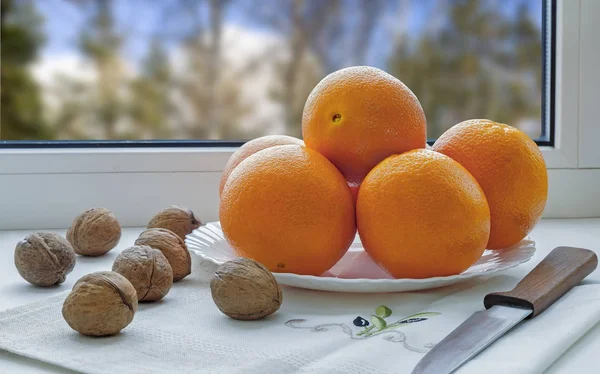 Στο Περβάζι Του Παραθύρου Πλάκα Πορτοκάλια Ένα Μαχαίρι Και Καρύδια — Φωτογραφία Αρχείου