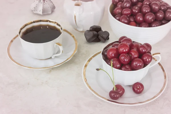 Café e cerejas em uma xícara na mesa . — Fotografia de Stock