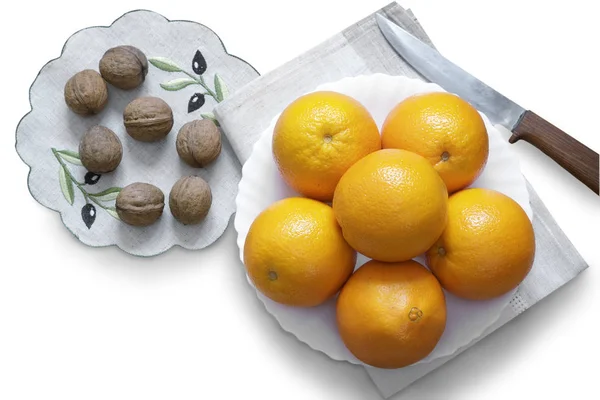 Oranges in the bowl and walnuts on a white background. — Stock Photo, Image