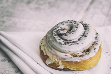 Bir peçete masaya iştah açıcı bir topuz, sır ve haşhaş tohumu ile kaplı olduğu.