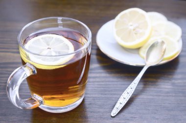 Bir cam fincan sıcak güçlü çay ve limon tablosunda yüzeyinde.