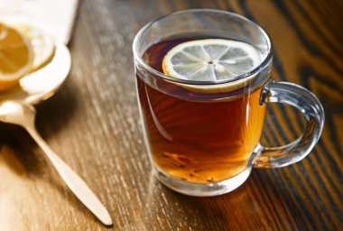 Bir cam fincan sıcak güçlü çay ve limon tablosunda yüzeyinde.