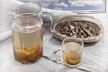 Pencere kenarında bir sürahi ve bardak Kayısı Komposto ile işte. Kurutulmuş elma sepetle.