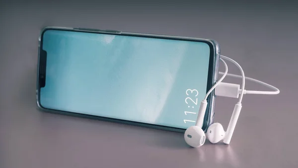 Smartphone y auriculares en un fondo gris . — Foto de Stock