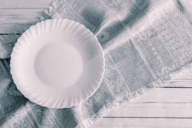 Çarşaf peçetede beyaz boş bir tabak.