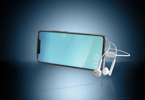 Smartphone et écouteurs sur fond bleu. — Photo