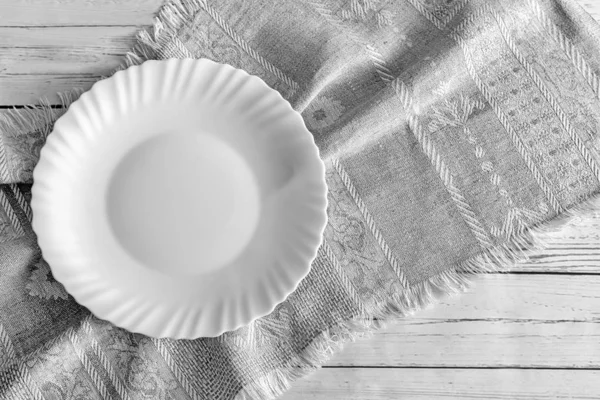Ein weißer leerer Teller auf einer Leinenserviette — Stockfoto
