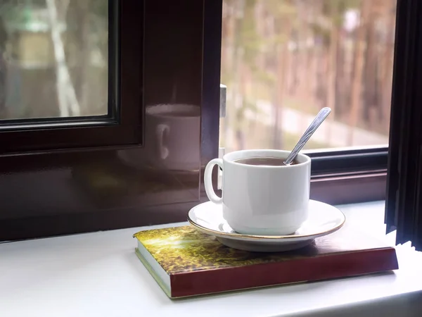 Une tasse de thé et un livre sur le rebord de fenêtre — Photo