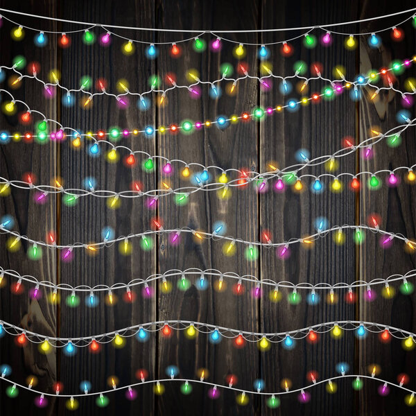 Set of color garland lights. Glowing christmas lights on wooden background. Includes 10 vector brushes festive strands of Christmas lights