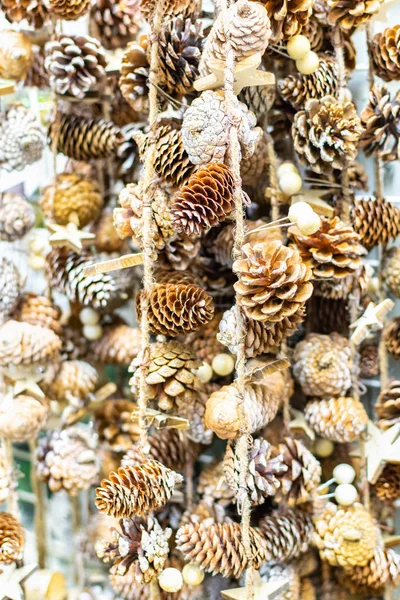 Karácsonyi öko koszorú fenyőtobozok és fából készült csillagok lóg egy juta kötél függőlegesen, nyaralás dekoráció háttér készült természetes anyagokból. — Stock Fotó