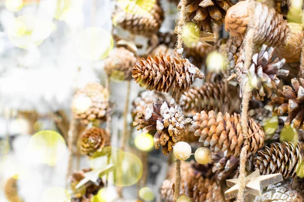 Christmas eco garland of pine cones and wooden stars hanging on a jute rope on the window with bokeh lights, holiday decoration background made of natural materials, copy space. — Stock Photo, Image