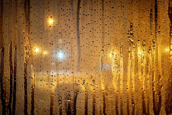 暗闇の中で黄色の街路灯と夜遅くに凝縮水の滴と窓 透明なガラスの背景を濡らす 液滴パターン — ストック写真