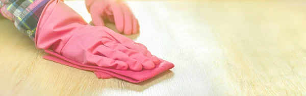 Temizlik kavramı. Pembe eldivenli bir kadın eli yumuşak bir bez tutar, ahşap zemini tozdan ve çamurdan siler. Ev temizliği, laminatın yüzey temizliği. Kopyalama alanı olan arkaplan.