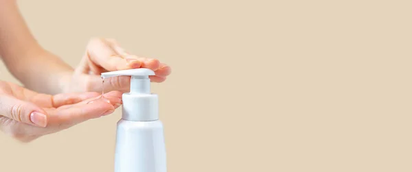 A woman press on a bottle with antibacterial gel to clean and wash hands of bacteria and virus close-up. The concept of protection and prophylaxis against coronavirus disease. Background, copy space.