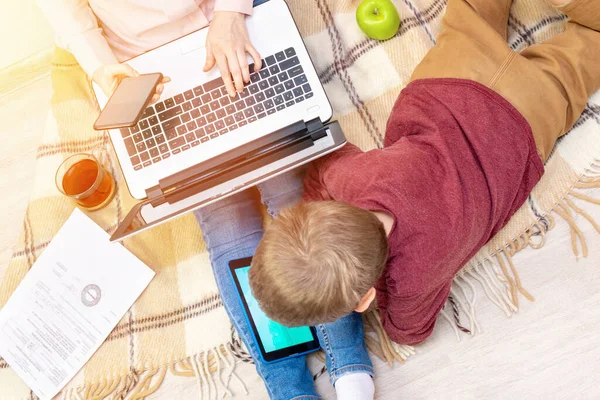 Güneşli bir günde bir kadın ve bir anaokulu öğrencisi yerde oturuyorlar. Annesi bir telefon tutuyor, evde çalışıyor ve oğlu bir tabletle oynuyor, uzaktan çalışma, serbest çalışma, çocuklar arasında çalışma, karantina...