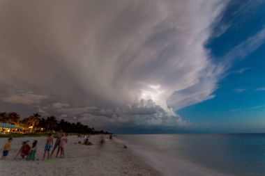 Naples beach and calm ocean during a lightning storm at sunset, Florida, USA. Amazing cloudscape during a big tropical storm in the Gulf of Mexico, close to Everglades National Park.Amazing lightning storm sunset and calmed ocean, at Naples beach, Fl clipart