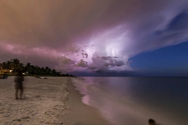 Naples beach and calm ocean during a lightning storm at sunset, Florida, USA. Amazing cloudscape during a big tropical storm in the Gulf of Mexico, close to Everglades National Park.Amazing lightning storm sunset and calmed ocean, at Naples beach, Fl