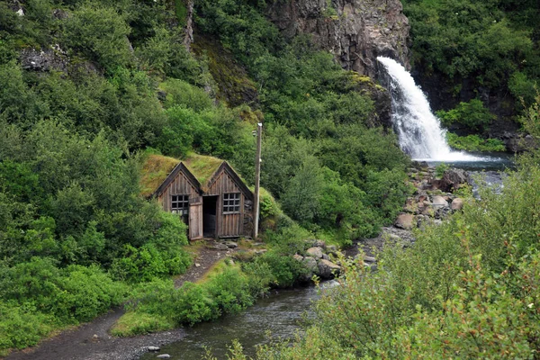 Staré stodoly nedaleko malého vodopádu na Islandu — Stock fotografie