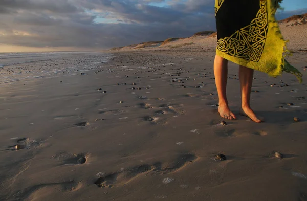 Pernas de uma menina ao pôr do sol na praia da costa atlântica — Fotografia de Stock