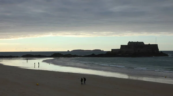 Pessoas solitárias na praia ao pôr do sol e vista para o forte Grand Be em Saint-Malo — Fotografia de Stock