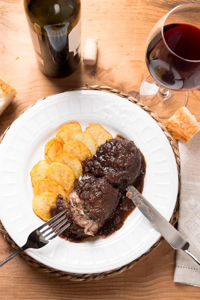 Demlenmiş Domuz eti yanakları kırmızı şarap ve patates kızartması ile — Stok fotoğraf