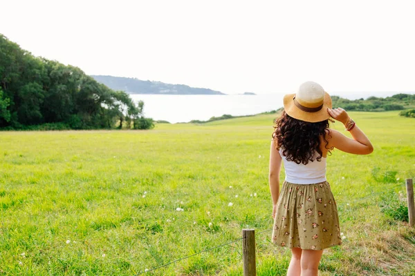 Mladá žena s pamela uvažuje o zelená krajina — Stock fotografie