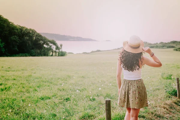 Jonge vrouw met pamela overweegt groene landschap — Stockfoto