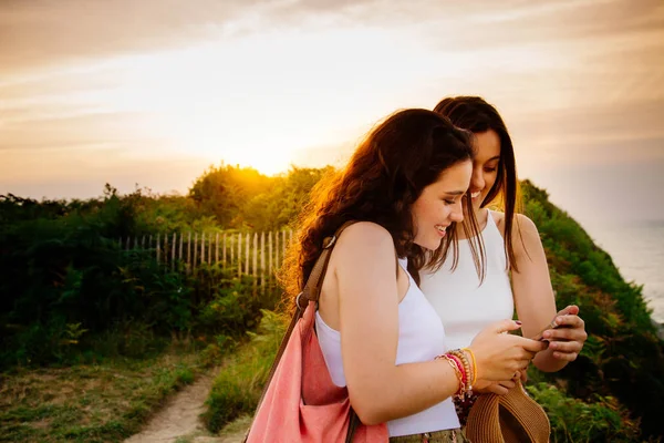 Meninas usando um smartphone ao pôr do sol — Fotografia de Stock