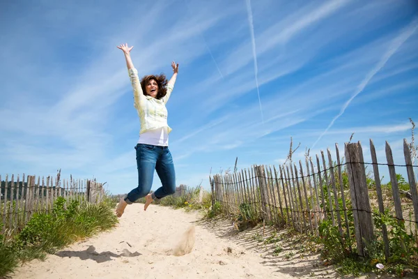 Femme âgée migrante sautant sur la plage — Photo