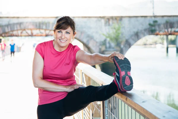 Middle aged woman stretching legs on a trail