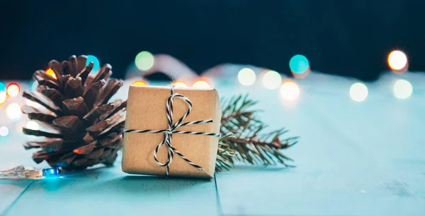 Weihnachtsgeschenk mit Tannenzapfen, Tannenzweig und Lichtern Bokeh — Stockfoto