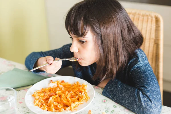 Маленькая девочка ест макароны с томатным соусом — стоковое фото