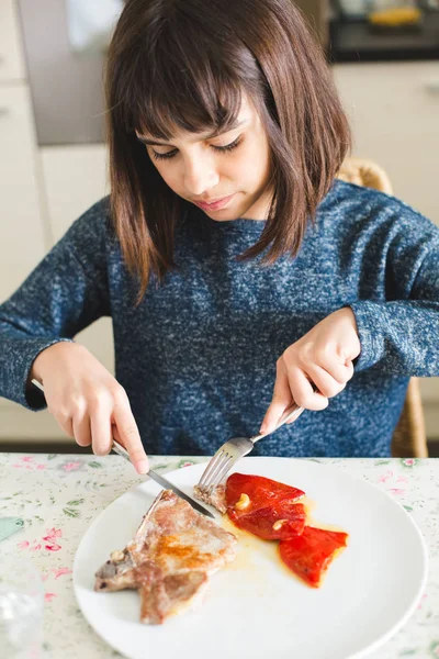 Kleines Mädchen isst Schweinekotelett mit Paprika — Stockfoto