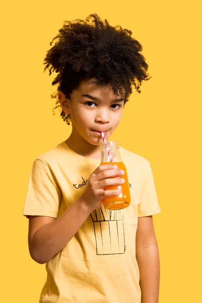Lindo niño bebiendo jugo de naranja con una paja — Foto de Stock