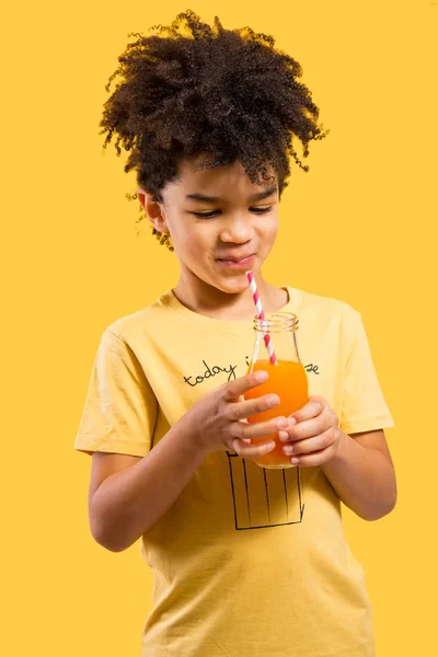 Süßer kleiner Junge trinkt Orangensaft mit einem Strohhalm — Stockfoto