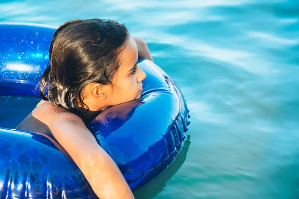 Glückliches kleines Mädchen, das mit einem Ring im Wasser schwimmt — Stockfoto