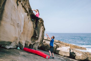 Rock climbers climbing cliffs at the coast clipart
