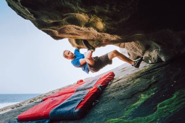 Young climber man climbing at the coast clipart