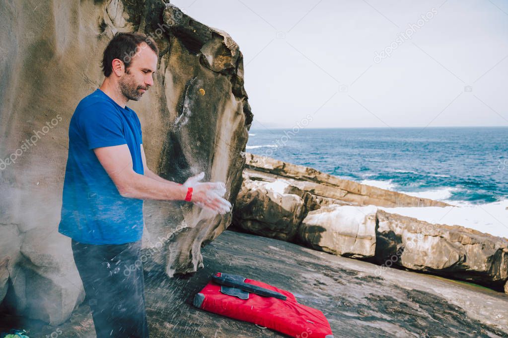 Rock climber man coating hands in magnesium 